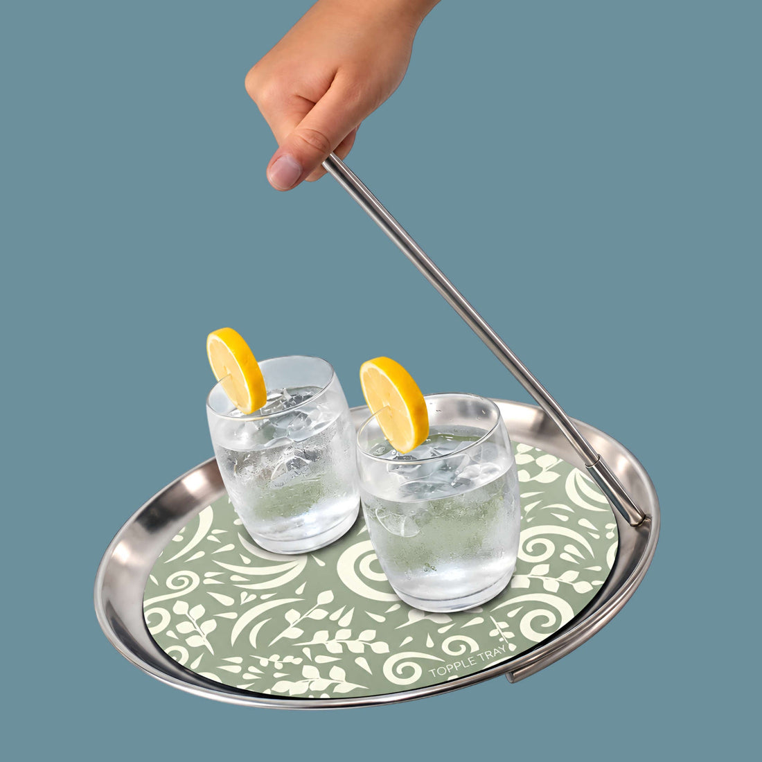 Topple Tray carrying two glasses of lemon water on the sage botanical mat